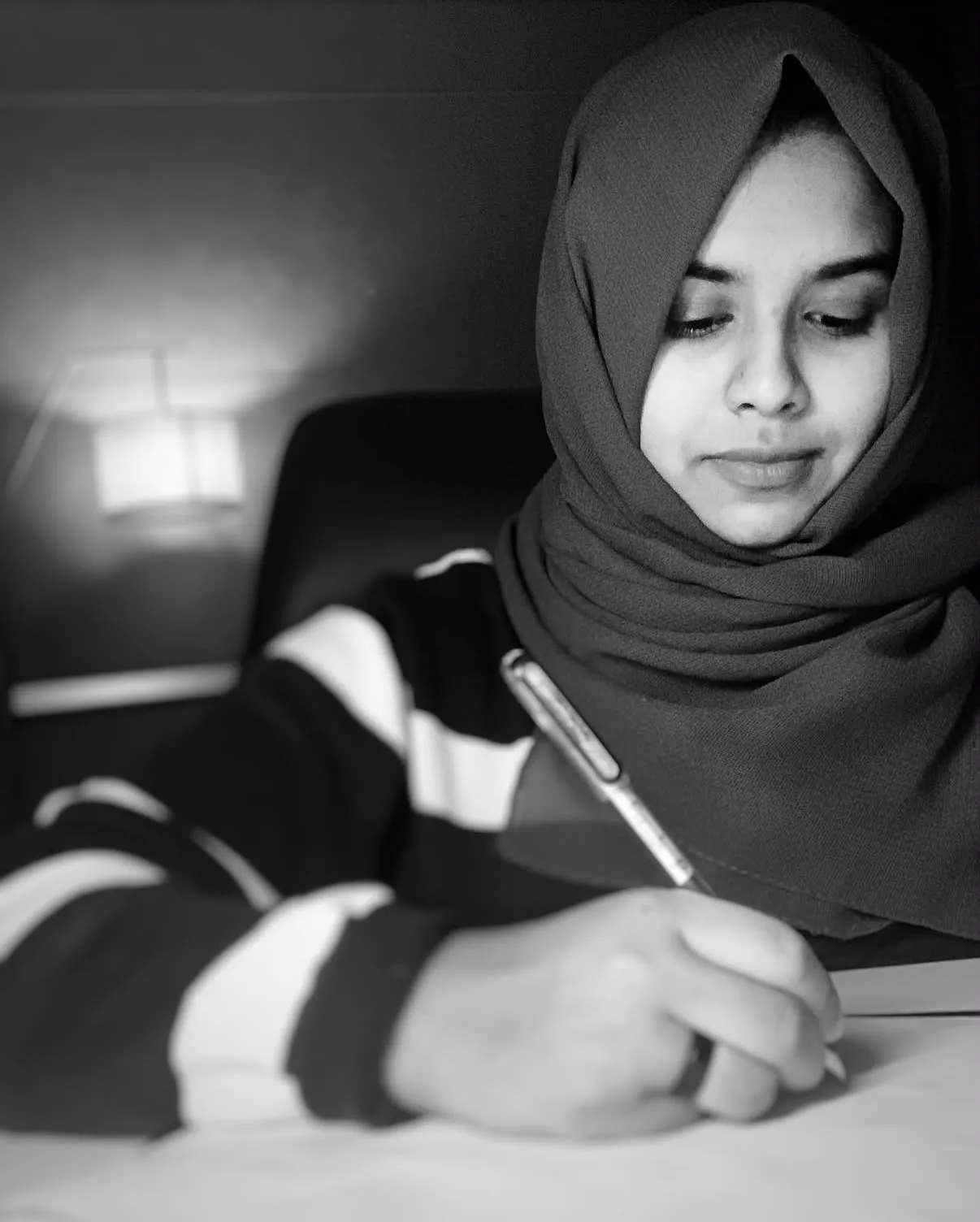 The author writing at a desk by lamplight